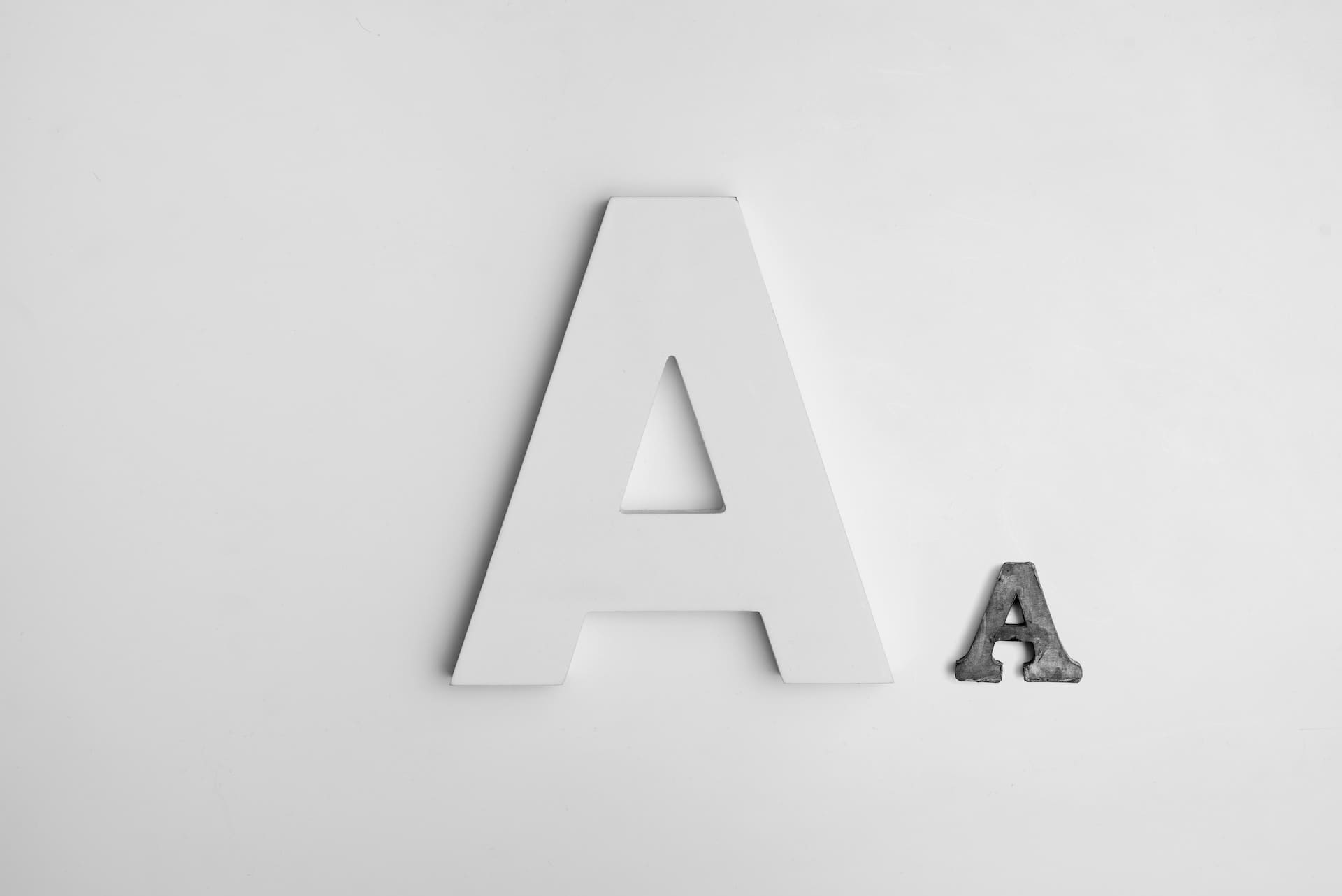 Two different sizes of letter A - the one in the center is Off-White in colour and about 5 times bigger than the A on its right in grey colour..